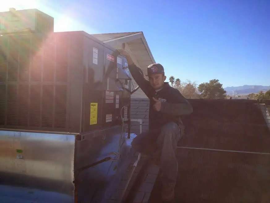 HVAC technician performing AC Tune-Up on a rooftop unit in Greenville